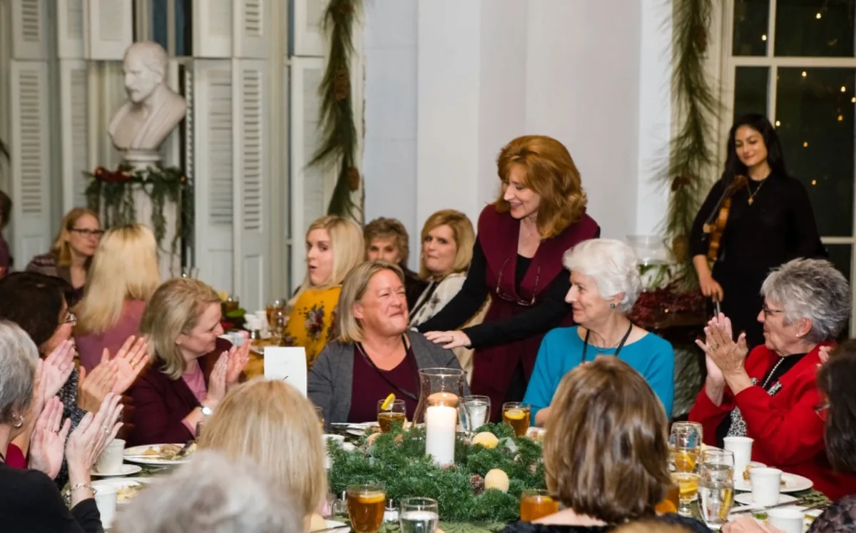 Tamera Alexander greeting guests at a dinner table during the Southern Mansion Reader Weekend