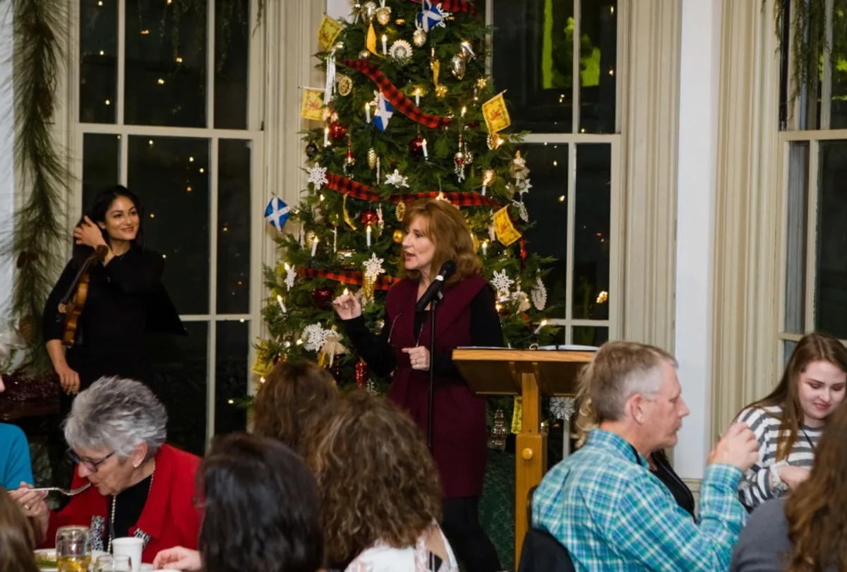 Tamera Alexander speaking to attendees beside a Christmas tree during the Southern Mansion Reader Weekend