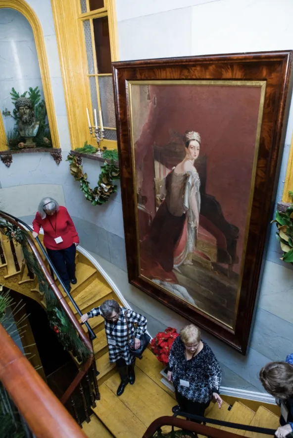 Guests descending the grand staircase past a portrait during the Southern Mansion Reader Weekend