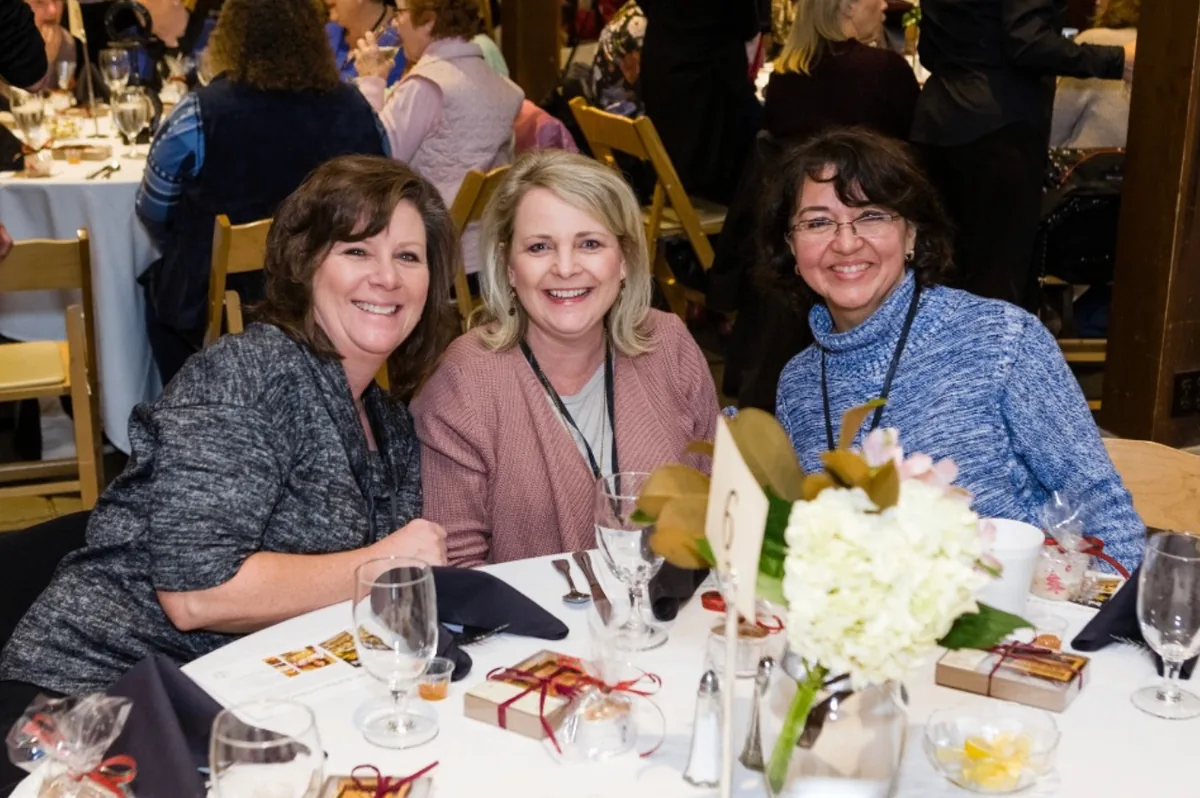 Three Southern Mansion Reader Weekend attendees smiling together at their dinner table