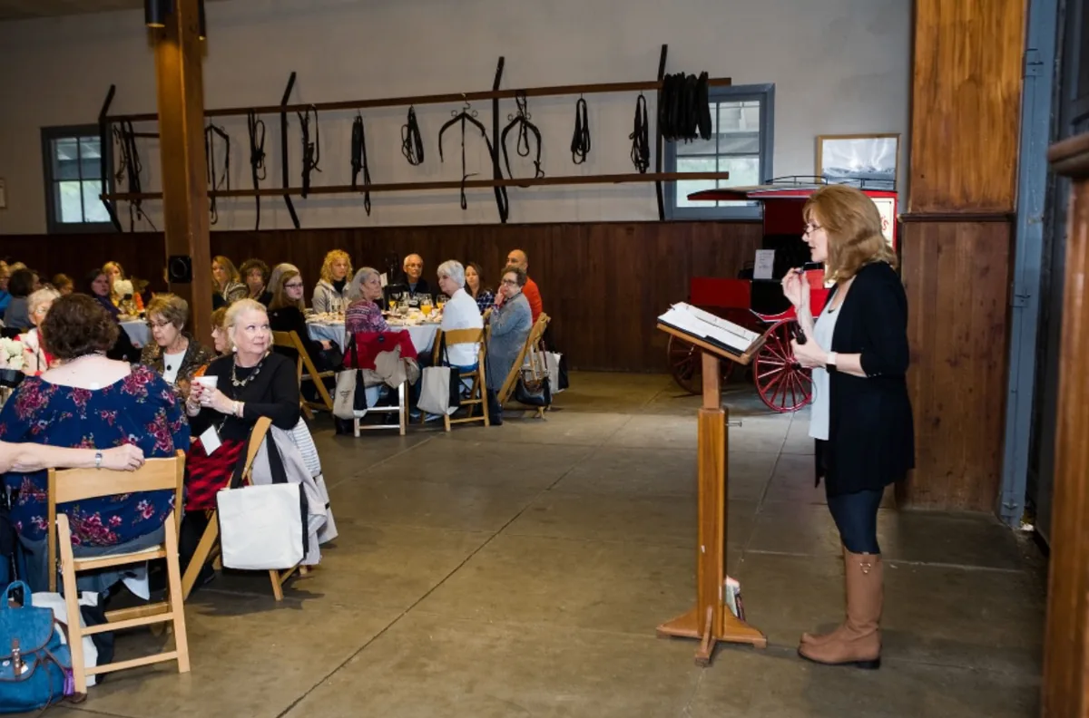 Tamera Alexander speaking to guests from a lectern during the Southern Mansion Reader Weekend