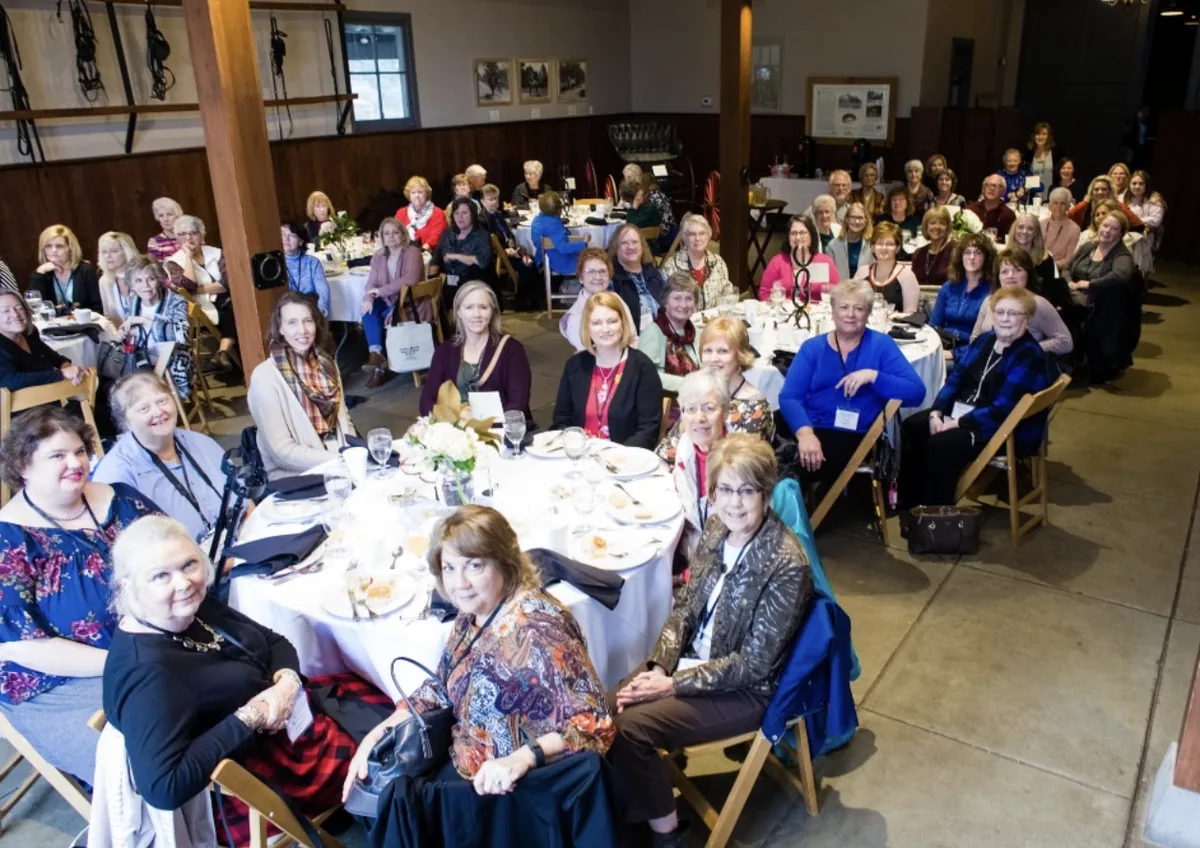 A wide view of Southern Mansion Reader Weekend attendees gathered for dinner inside the carriage house