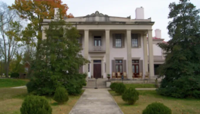 Belle Meade Plantation in autumn with golden trees framing the columned facade.