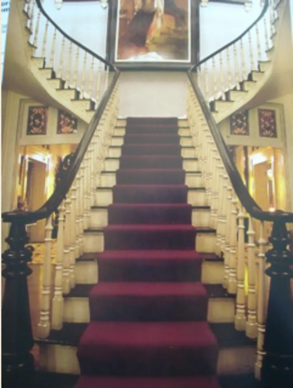 Belmont Mansion's grand cantilevered staircase with deep red runner and curved banisters.