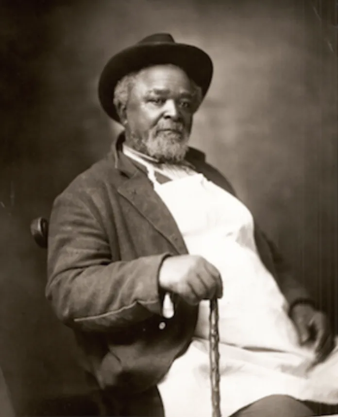 Robert Green, known as Uncle Bob, head hostler at Belle Meade Plantation, seated with a cane and wearing his trademark white apron.