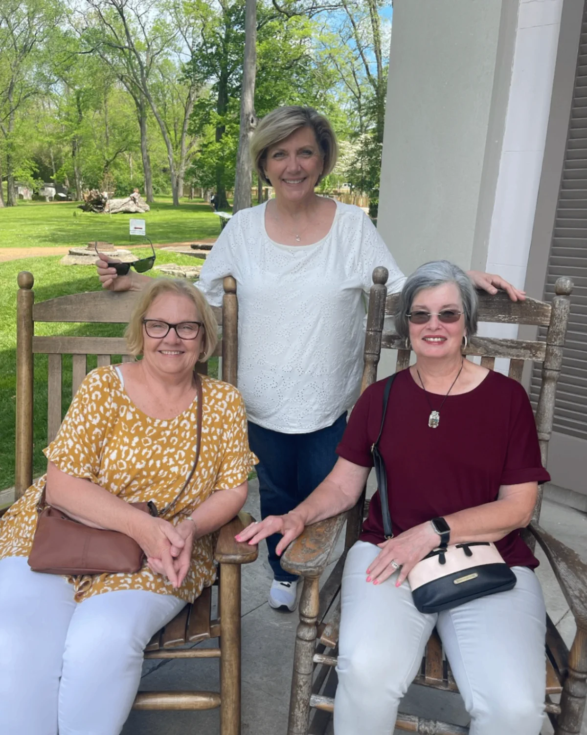 Three visitors seated and standing in rocking chairs during a Belle Meade visit.