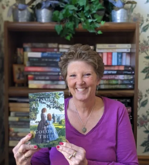 A reader friend smiling while holding Tamera Alexander's novel Colors of Truth.